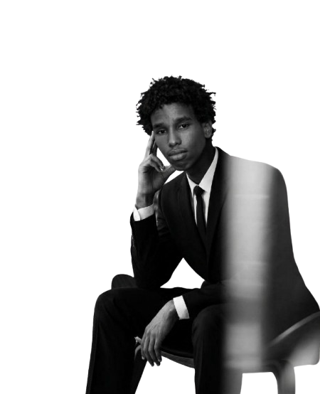 Yusuf, seated in a black suit, black-and-white portrait